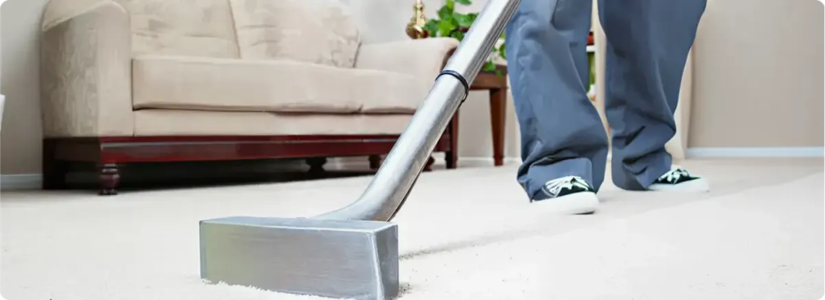 Carpet cleaning technician using a hot-water extraction wand on a light-colored carpet in a living room, Gilbert, AZ.